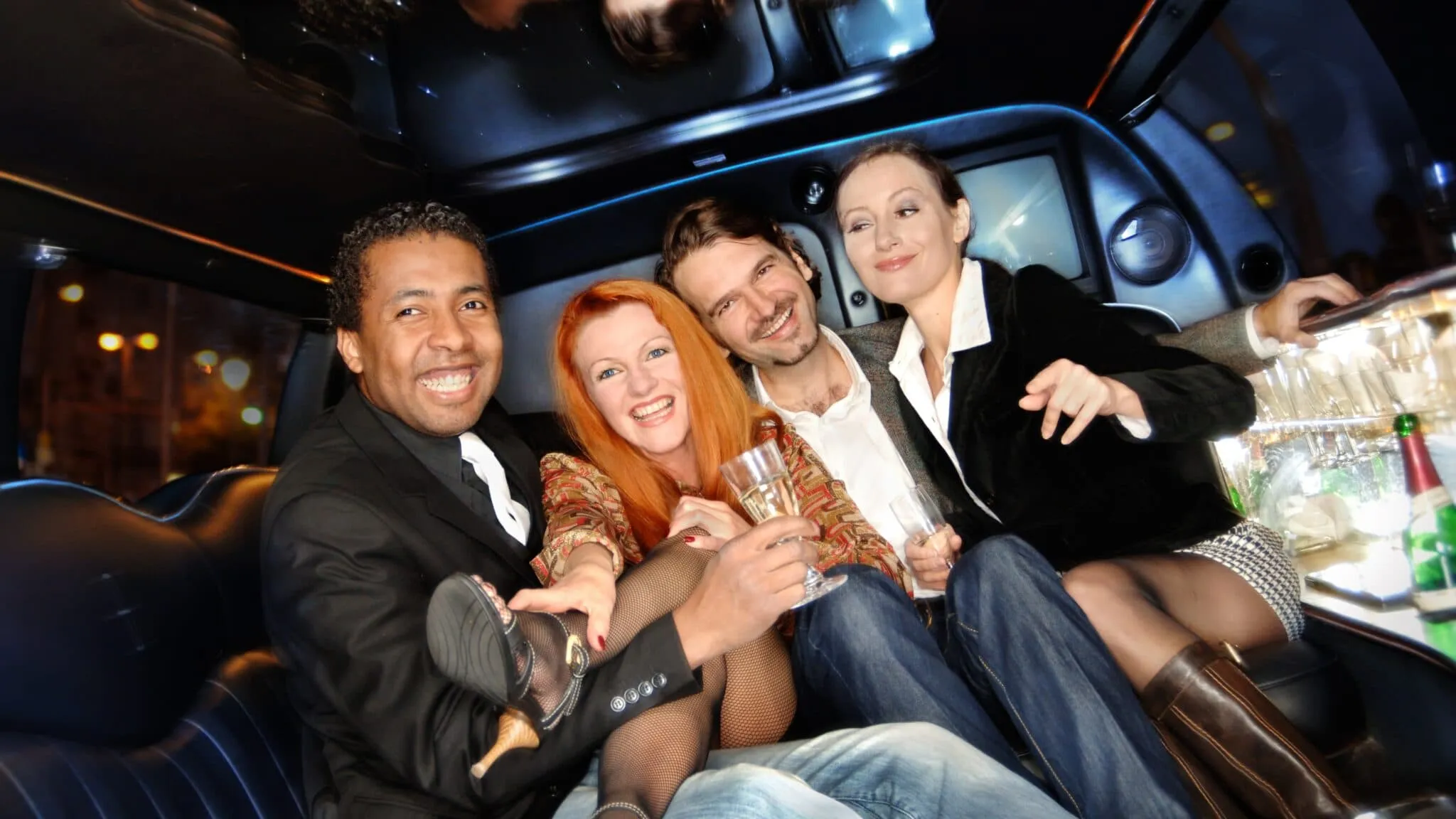 Group of friends dressed elegantly, celebrating and enjoying champagne inside a luxury limousine with a joyful and lively atmosphere.