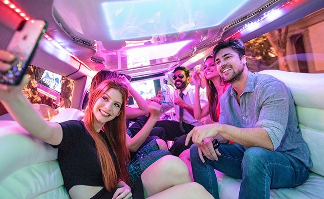 Group of friends dressed elegantly, celebrating and enjoying champagne inside a luxury limousine with a joyful and lively atmosphere.
