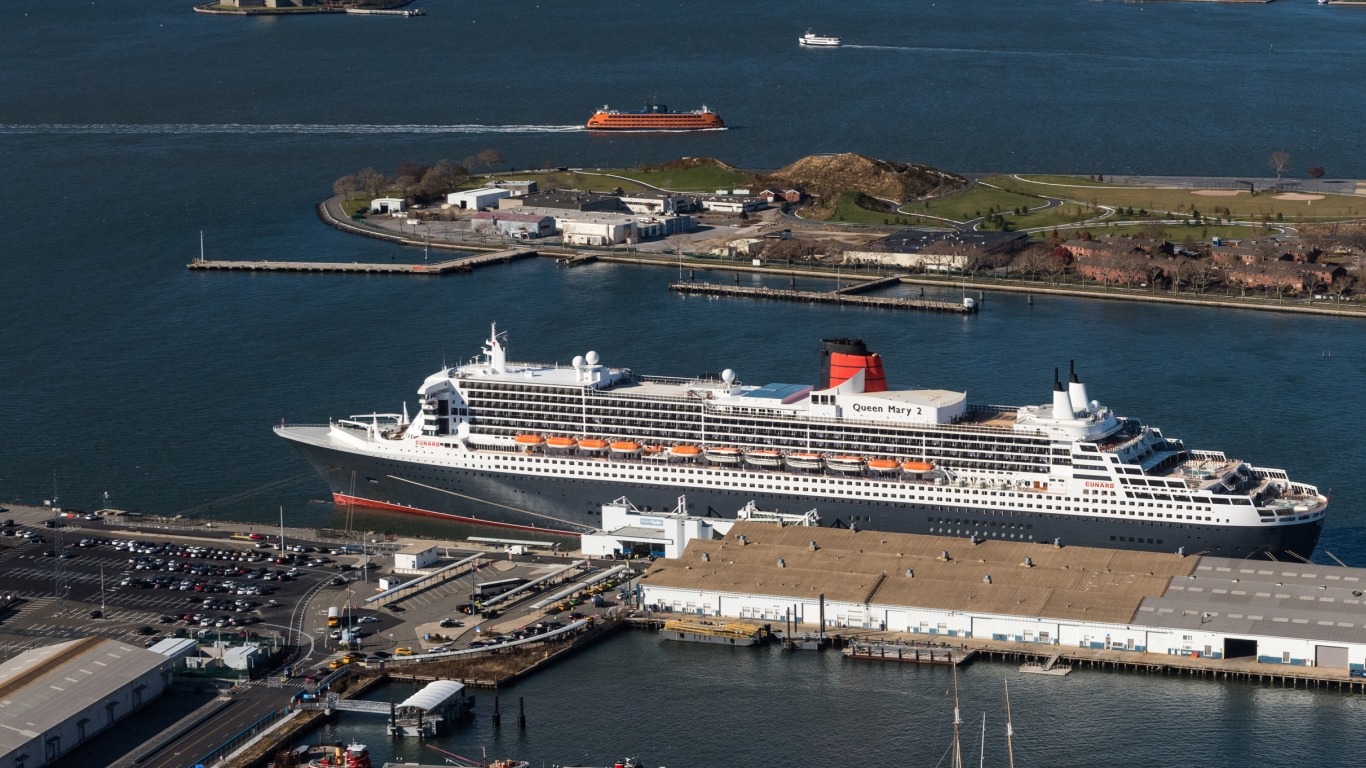 Cruise ship Queen Mary 2 docked at a port terminal with surrounding water and buildings.