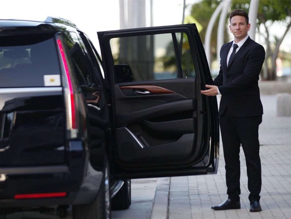 Professional chauffeur holding the door of a luxury SUV, providing welcoming and elegant private transfer service.
