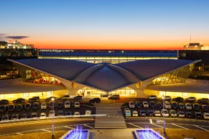 The iconic TWA Flight Center at JFK Airport during sunset, its retro-futuristic architecture illuminated under a vibrant sky.
