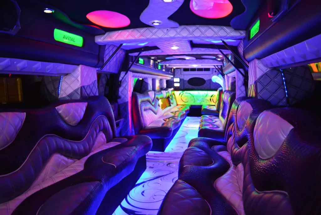 Interior of a luxury party limousine with vibrant neon lighting, plush seating, and modern entertainment features.
