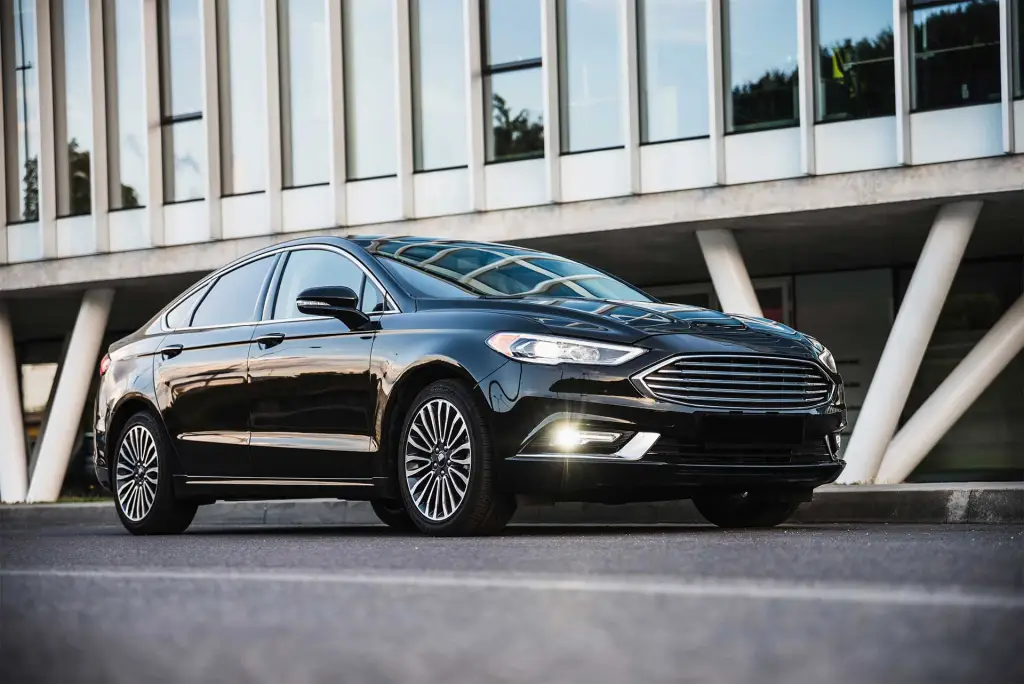 Black luxury sedan parked in front of a modern building, representing Newark Liberty Airport (EWR) car service.
