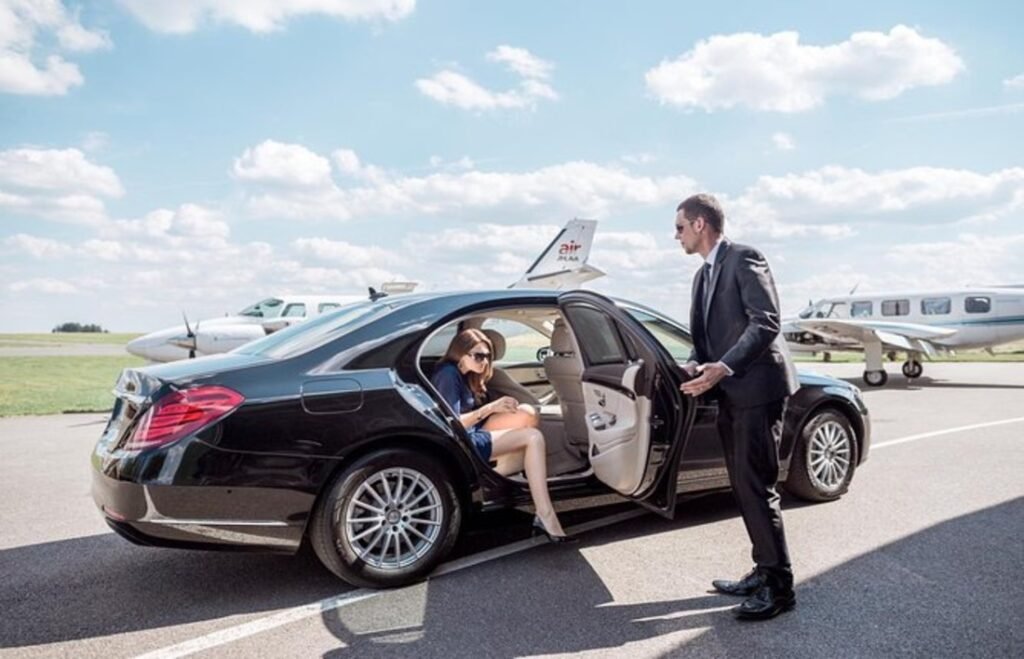 Luxury chauffeur service at a private airport runway, elegant woman stepping out of a black Mercedes-Benz sedan.