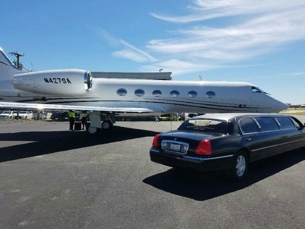 Luxury black limo next to a Gulfstream jet at the airport runway, showcasing JFK Limo Service's premium transfers.