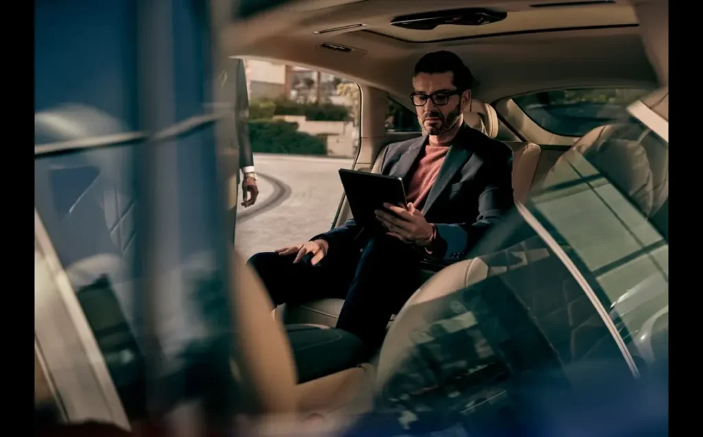 Business executive working on a tablet inside a luxury car during a corporate travel service in Manhattan.