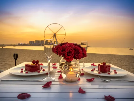 How to Celebrate Sweetest Day? 20 Romantic beach dinner at sunset with red velvet cakes, roses, champagne glasses, and a glowing candle centerpiece.