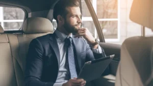 Business professional riding comfortably in the back of a luxury vehicle, working on a laptop during corporate travel.